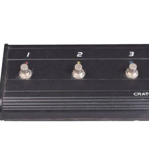 May include: Black Crate foot pedal with three silver footswitches labeled 1, 2, and 3. Each switch has a colored indicator light. The word "CRATE" is printed on the bottom right.