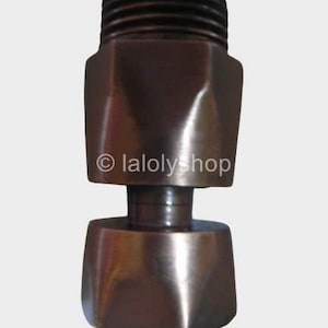 May include: A bronze-coloured metal shower head adapter with a hexagonal shape. The adapter has a threaded end on both sides.