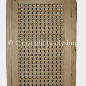 Peut inclure: Une porte de placard en bois avec un motif décoratif tissé en forme de grille. La porte est de couleur brun clair et présente un design simple et rustique.