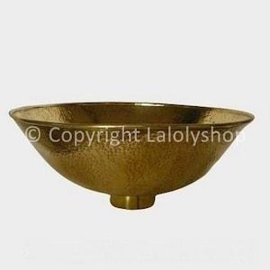 Peut inclure: Un bol en laiton martelé avec une base large et arrondie et un bord légèrement évasé. Le bol a une finition martelée texturée et un intérieur lisse et poli.