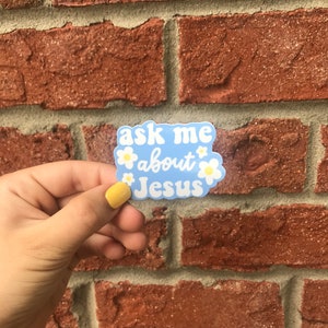May include: A blue sticker with white daisies and the text "ask me about Jesus" in a white outline.