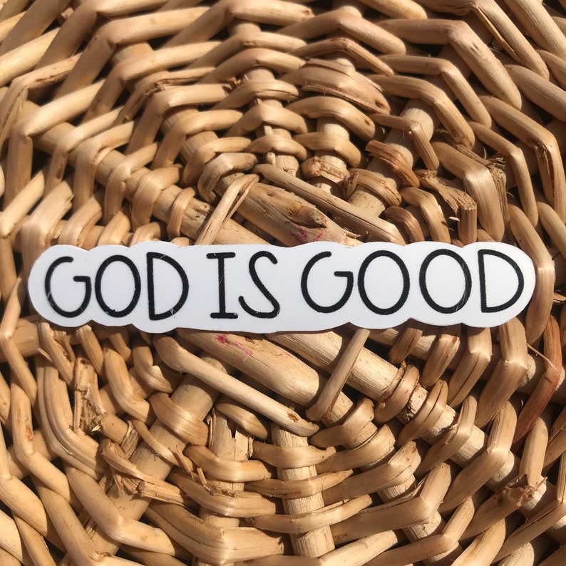 Puede incluir: Pegatina blanca con texto negro que dice "GOD IS GOOD" sobre un fondo de mimbre tejido.