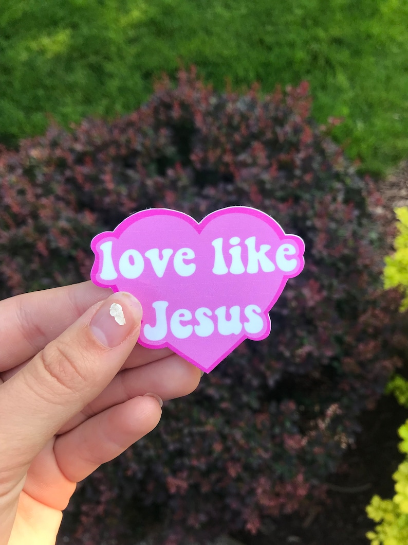 May include: Pink heart-shaped sticker with the text "love like Jesus" in white letters.