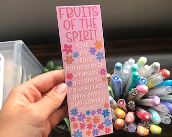 May include: Pink bookmark with the text "Fruits of the Spirit" and a list of the fruits of the spirit: love, joy, peace, forbearance, kindness, goodness, faithfulness, gentleness, self-control. The bookmark is decorated with colorful flowers.