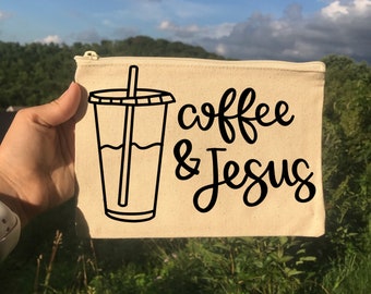 May include: A beige canvas zippered pouch with a black outline of a coffee cup with a straw and the text "coffee & Jesus" in black cursive.