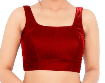 May include: A sleeveless, burgundy velvet top with a square neckline. The bodice is fitted, and the fabric has a soft, luxurious sheen. The top is a solid color and appears to be a formal or semi-formal garment.