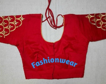 May include: Red silk blouse with gold embroidery on the sleeves and neckline. The blouse has a tie-up back and is a traditional Indian garment.