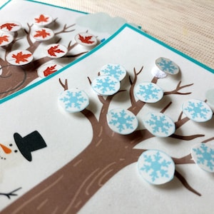 May include: A brown tree with blue snowflake stickers on the branches. A snowman is in the bottom left corner of the image.