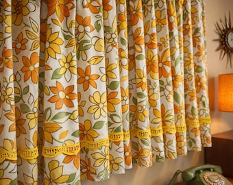 Puede incluir: Cortinas con estampado floral en tonos amarillos, naranjas y verdes sobre fondo blanco. Cuentan con un ribete de encaje amarillo. El diseño evoca una estética vintage, ideal para una habitación retro.