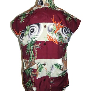 May include: A maroon and white striped short-sleeved shirt with a colorful print of dragons, tigers, and bamboo. The shirt has a button-up front and a pocket on the left side.