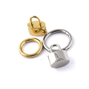 May include: Three gold and silver body jewellery pieces. A gold padlock, a gold hoop, and a silver hoop.