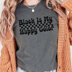 May include: A dark gray t-shirt with the text "Black is my Happy Color" in black lettering with a checkered pattern behind the text.