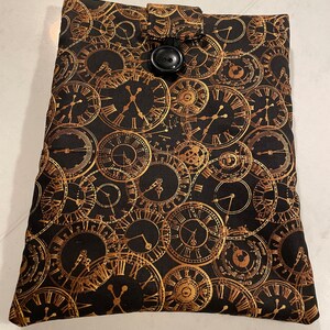 Peut inclure: Une housse de livre en tissu noir avec un motif d'horloge doré. La housse est dotée d'une fermeture à bouton noir.