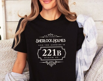 May include: Black t-shirt with white text that reads "The name's Sherlock Holmes and the address is 221B Baker St."