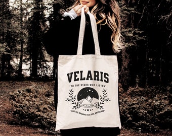 May include: A white canvas tote bag with black text and a graphic design. The text reads "Velaris" "To the stars who listen" "City of Starlight" "And the dreams that are answered".
