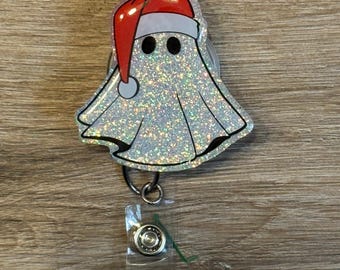 May include: A sparkly white ghost wearing a red Santa hat, attached to a clear plastic retractable badge holder.