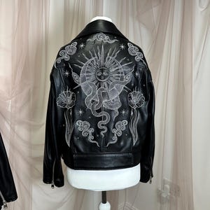 Faux leather jacket featuring stunning metallic silver embroidery in a celestial design. Intricate embroidery showcases a cosmic sun, snake, moon and celestial stars, creating a bold statement jacket for astrology and celestial lovers. Custom made to order with optional colour changes, offering a unique, magical embroidered outerwear piece that stands out from the crowd.