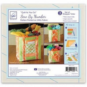 May include: A set of three "Quilt As You Go" Sew By Number shopper totes. The totes are made of utility fabric and feature a colorful patchwork design. The instructions include a grid pattern for easy sewing. The totes are finished at 13" x 13" x 10" high.