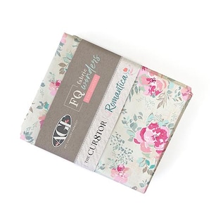 Può includere: Un fascio di quadrati di tessuto floreale. Il tessuto presenta uno sfondo chiaro con rose rosa e rosse, foglie verdi e accenti blu. Il fascio è avvolto con una fascia di carta marrone con la scritta "FQ fabric wonders" e "The CUR8TOR Romantica."