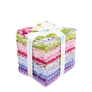 Könnte beinhalten: Ein Stapel quadratischer Stoffstücke mit Blumenmuster in Rosa, Lila, Grün und Weiß, gebunden mit einem weißen Band. Das Band ist mit grünen Blättern und Blumen bedruckt und trägt den Text "Riley Blake Designs".