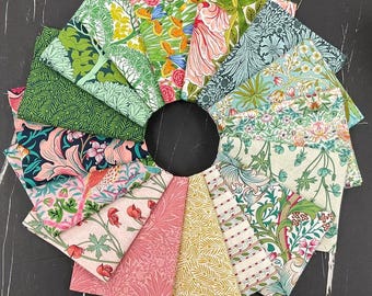 May include: A collection of fabric squares arranged in a circular pattern. The fabrics feature various floral and botanical designs in shades of green, pink, yellow, and blue. The arrangement is set against a dark, textured background.