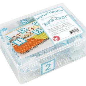 Może przedstawiać: Przezroczyste plastikowe pudełko do przechowywania zawierające specjalne klipsy do znakowania AlphaClippies. Pudełko zawiera klipsy z literami A, B i C oraz cyframi 1, 2, 3 i 5. Klipsy są przeznaczone do etykietowania i łączenia tkanin do projektów pikowania.