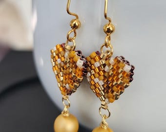 Pendientes artesanales en forma de corazón color miel y oro con una elegante perla colgante.