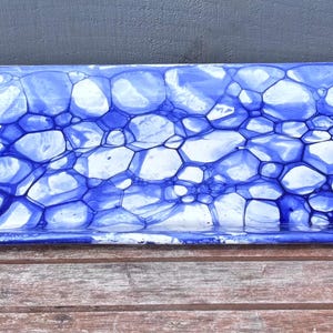 May include: A rectangular serving tray with a blue and white abstract pattern. The tray has rounded corners and a glossy finish. The design resembles a network of interconnected cells or bubbles.