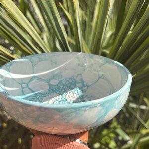 Puede incluir: Un cuenco de cer&aacute;mica redondo con una base blanca y un patr&oacute;n de burbujas de color azul claro en las superficies interior y exterior. El cuenco tiene un acabado liso y brillante con una forma circular constante y un borde curvado.