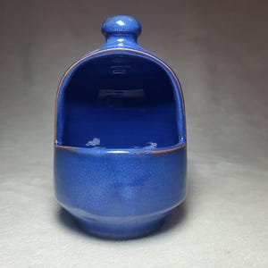 May include: A blue ceramic salt cellar with a rounded top and a small opening for pouring salt.