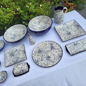 May include: A set of blue and white ceramic dishes with intricate floral patterns. The set includes a large bowl, a pitcher, a butter dish, and several smaller bowls and plates.