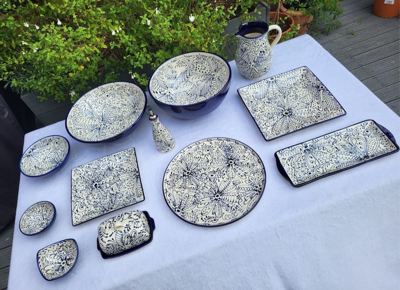 May include: A set of blue and white ceramic dishes with intricate floral patterns. The set includes a large bowl, a pitcher, a butter dish, and several smaller bowls and plates.