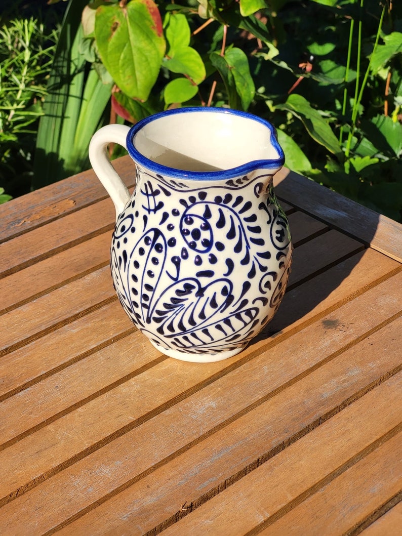 Hand-painted Spanish ceramic small jug featuring a traditional blue and white floral pattern. This authentic Mediterranean pottery has a glossy glazed finish and intricate artisan detailing.