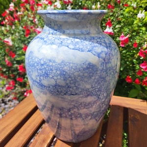 May include: A white ceramic vase with a blue and white bubble design. The vase has a round body and a wide mouth.