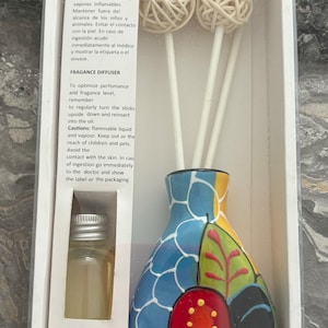 May include: A ceramic diffuser with a colourful floral design. The diffuser comes with a bottle of fragrance oil and sticks to disperse the scent. The diffuser is in a white box with instructions for use.