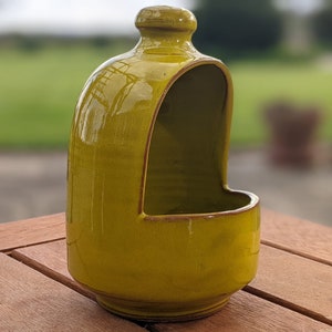 May include: A yellow ceramic salt cellar with a lid. The cellar has a rounded shape and a smooth, glossy finish.