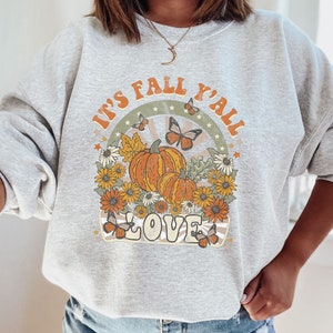 Pode incluir: Uma camisa de moletom cinza com uma estampa gr&aacute;fica retr&ocirc; que diz "It's Fall Y'all Love" com ab&oacute;boras, borboletas e flores.