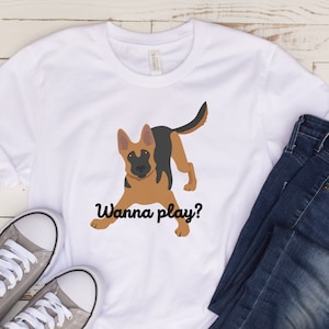 May include: White t-shirt with a cartoon German Shepherd dog illustration and the text "Wanna play?" printed on the front.
