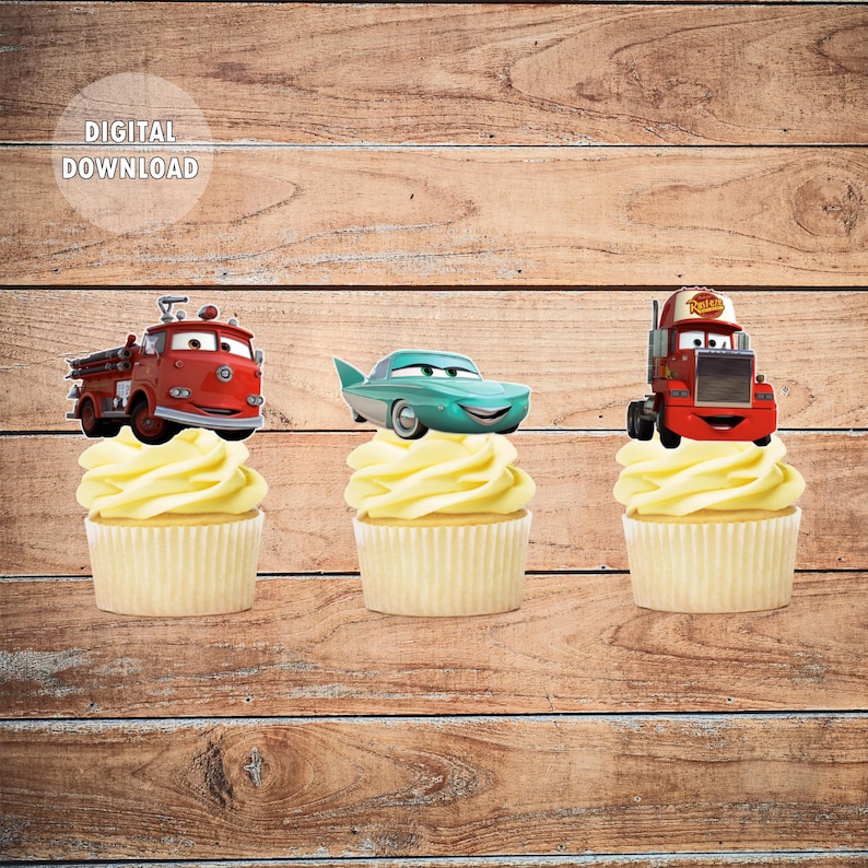 May include: Three cupcake toppers featuring characters from the Disney Pixar movie Cars. The toppers are a red fire truck, a teal sports car, and a red tow truck. The toppers are on top of cupcakes with white frosting.