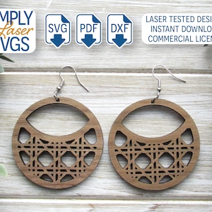 May include: A pair of wooden earrings with a geometric design. The earrings are brown and have a circular shape with a cutout in the center. The earrings are hanging from silver hooks.