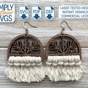 May include: A pair of wooden earrings with a delicate floral design and a white macrame tassel. The earrings are laser cut and have a natural wood finish.