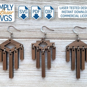 May include: Three pairs of laser cut wooden earrings with geometric designs. Each earring features a top piece with a unique shape and multiple dangling rectangular pieces. The earrings are brown and have silver hooks.