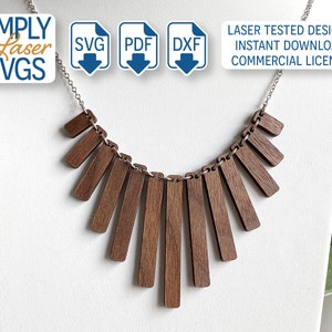 May include: A wooden necklace with a geometric design. The necklace is made of multiple rectangular pieces of wood that are arranged in a fan shape. The necklace is on a silver chain.