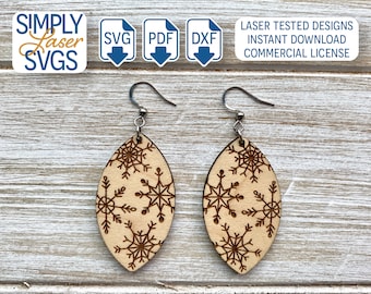 May include: A pair of wooden earrings with a snowflake design. The earrings are oval shaped and have a silver hook.