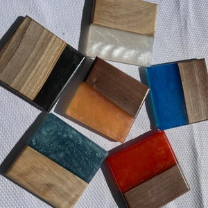 Puede incluir: Seis posavasos diferentes hechos de madera y resina. Los posavasos son de varios colores, incluyendo azul, naranja, rojo y blanco. Cada posavasos tiene una base de madera y una parte superior de resina.