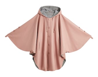 May include: A dusty rose hooded cape with a smooth finish, featuring a front button closure, side pockets, and a black and white houndstooth patterned lining. The garment has wide, flared sleeves with button details along the outer edges.