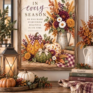May include: A framed wall art print featuring a floral arrangement in a metal pitcher, three pumpkins with bows, and the text: IN every SEASON HE HAS MADE EVERYTHING BEAUTIFUL IN ITS TIME. ECCLESIASTES 3:11. The artwork displays autumn colors.