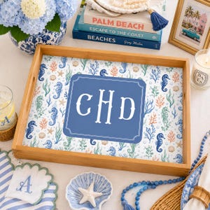 May include: A rectangular bamboo serving tray featuring a white background with a repeating pattern of blue seahorses, orange coral, green seaweed, and seashells. A large blue rectangular center panel displays the white monogram letters CHD.