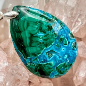 May include: A teardrop-shaped pendant featuring a polished surface with swirling patterns of deep forest green and vibrant turquoise blue. The stone is set with a silver-toned metal bail at the top, showcasing a smooth, glossy finish throughout.