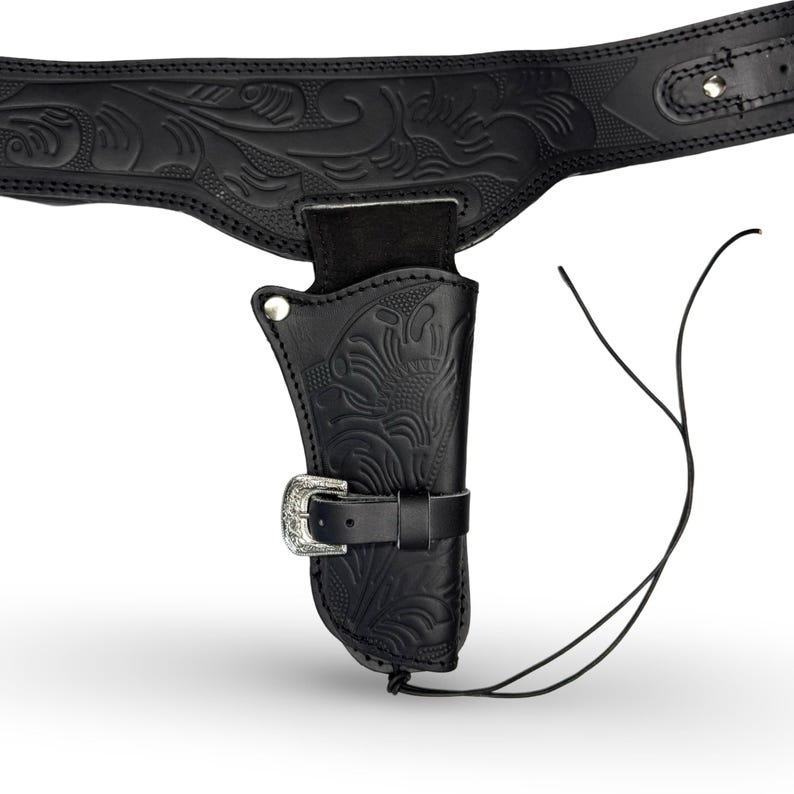 K&ouml;nnte beinhalten: Schwarzes Leder-Cowboy-Holster mit Blumenmuster und silberner Schnalle. Das Holster ist an einem schwarzen Lederg&uuml;rtel mit Blumenmuster befestigt.